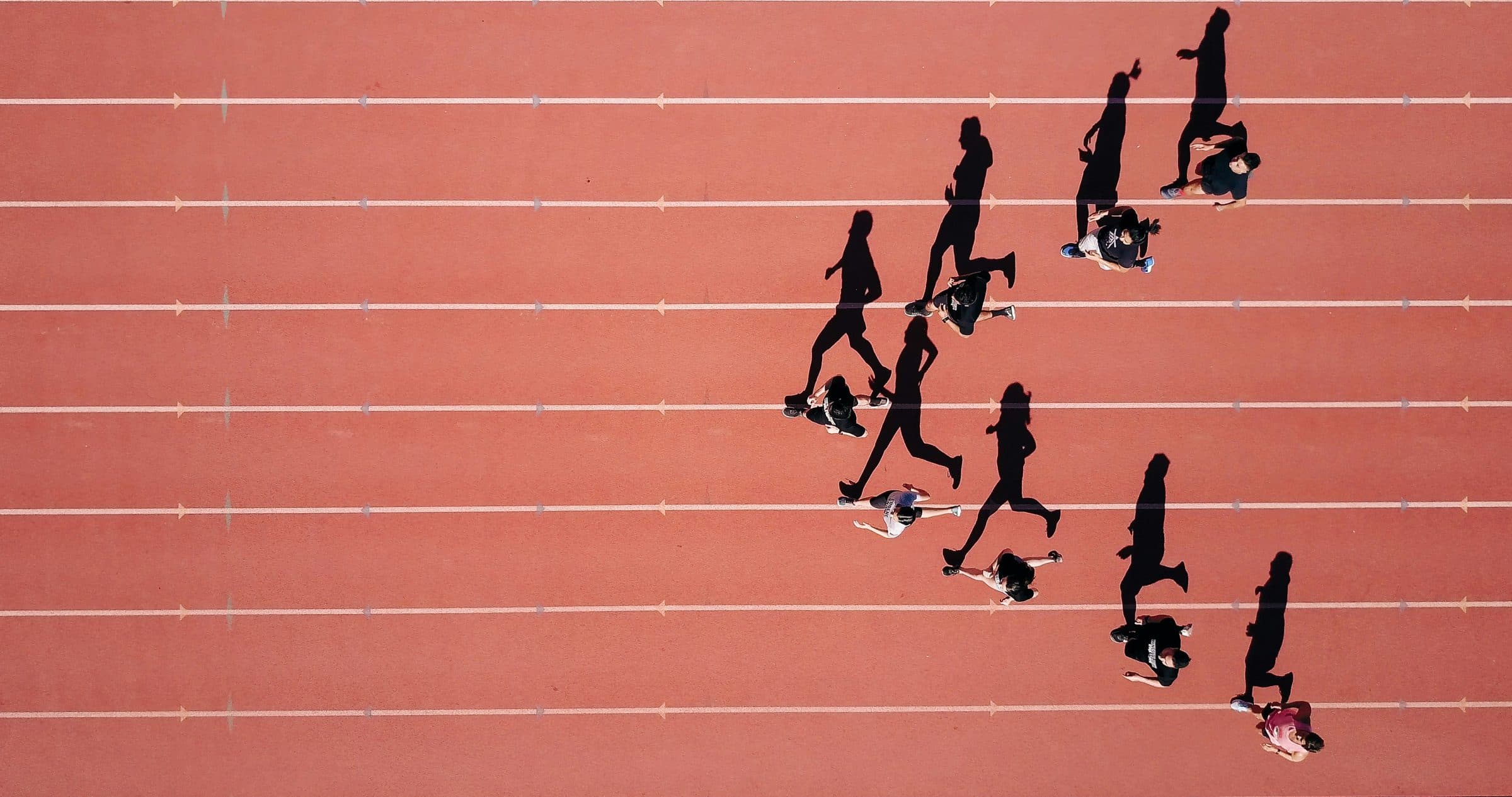 Vista aérea de uma pista de atletismo com um grupo correndo em formação